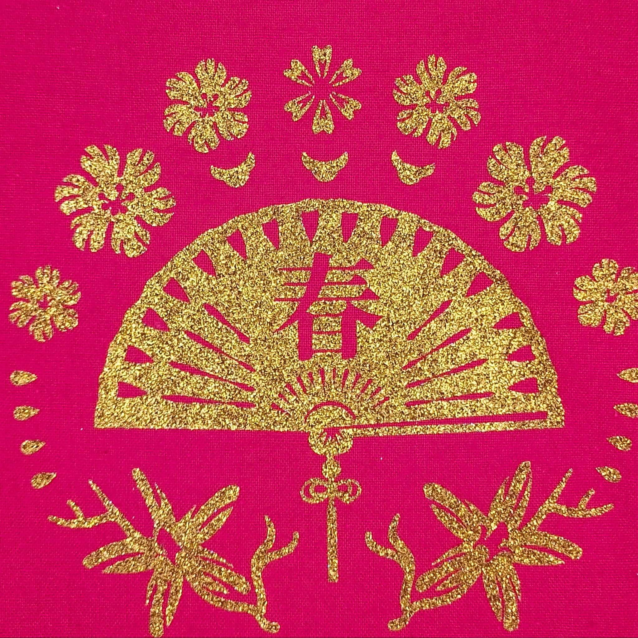 Glittering gold fan and floral pattern on a red fabric tote bag, captured in detailed close-up.