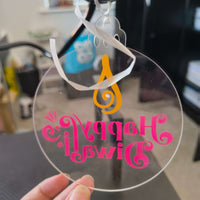 Back view of clear acrylic Happy Diwali bauble with pink mirrored text and orange diya flame, shown with white ribbon for hanging.