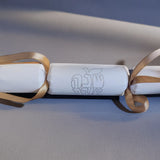 White cracker with gold foil Hebrew “Shana Tova” design and gold ribbon, displayed on a neutral background.
