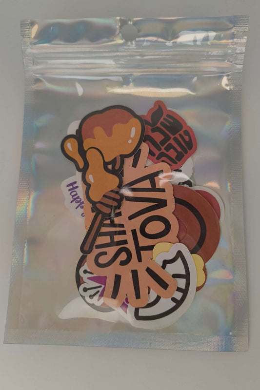 Sealed holographic bag containing Shana Tova Rosh Hashanah sticker pack with festive apple, honey, and pomegranate designs.