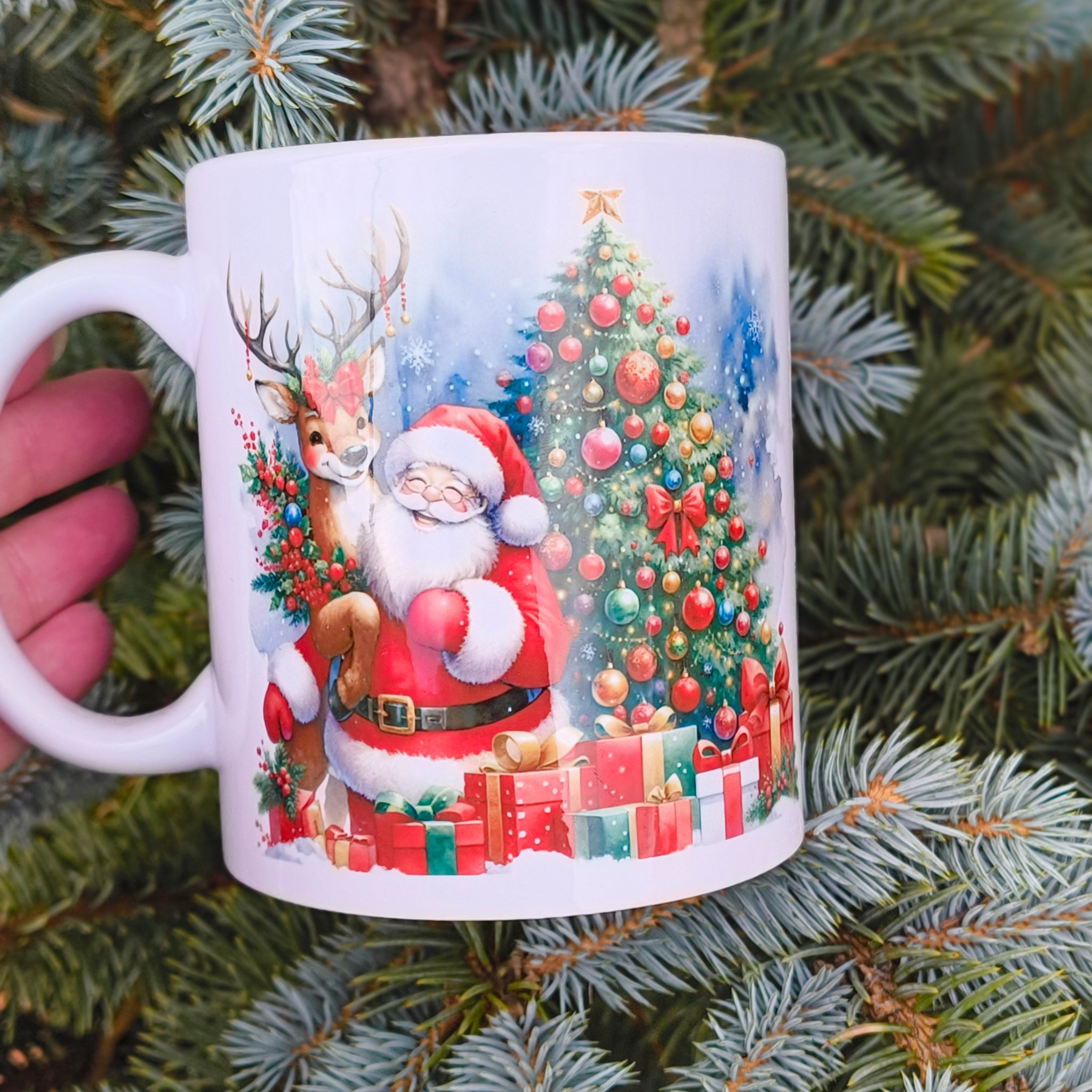 Christmas mug with Santa, reindeer, and decorated Christmas tree design, held outdoors among pine branches