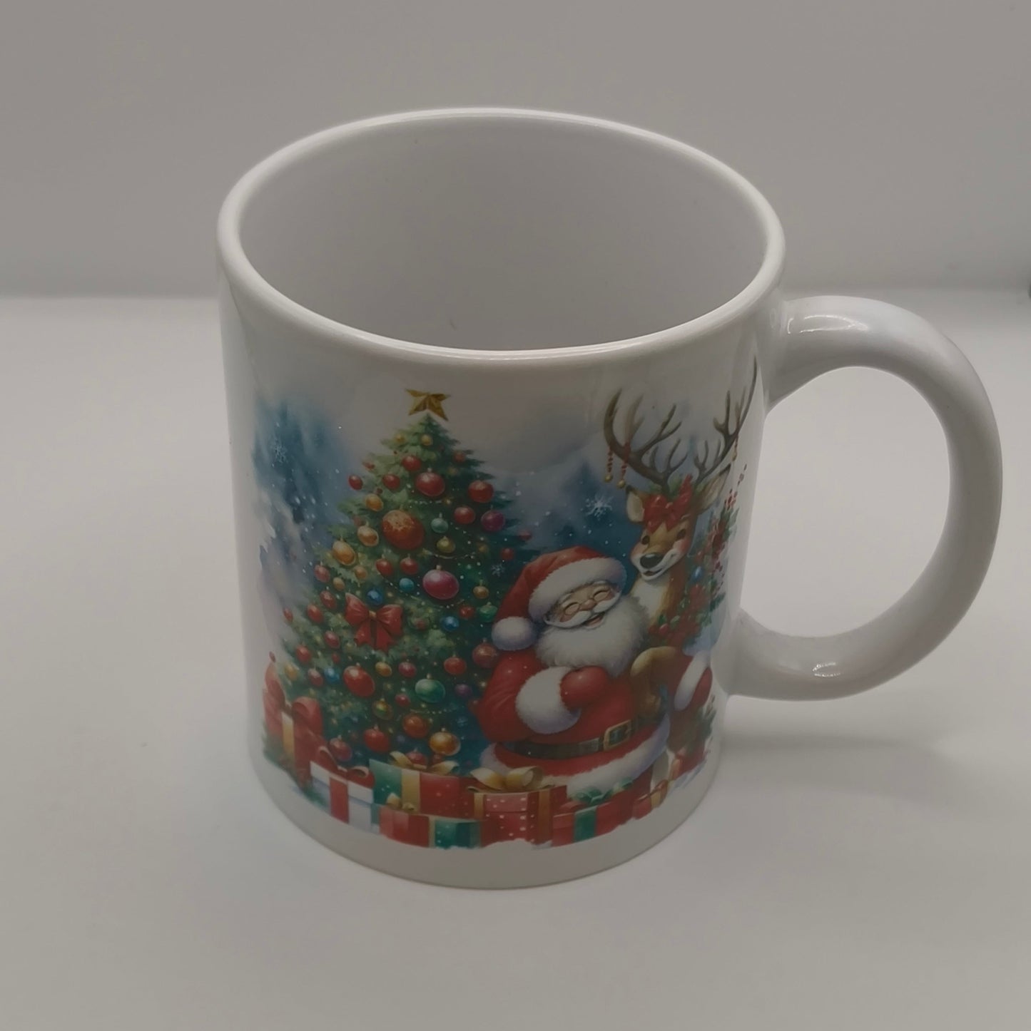 White Christmas mug with Santa Claus, reindeer, and decorated Christmas tree print, plain studio background