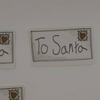 Close-up of To Santa sticker with holly and heart design, festive label style