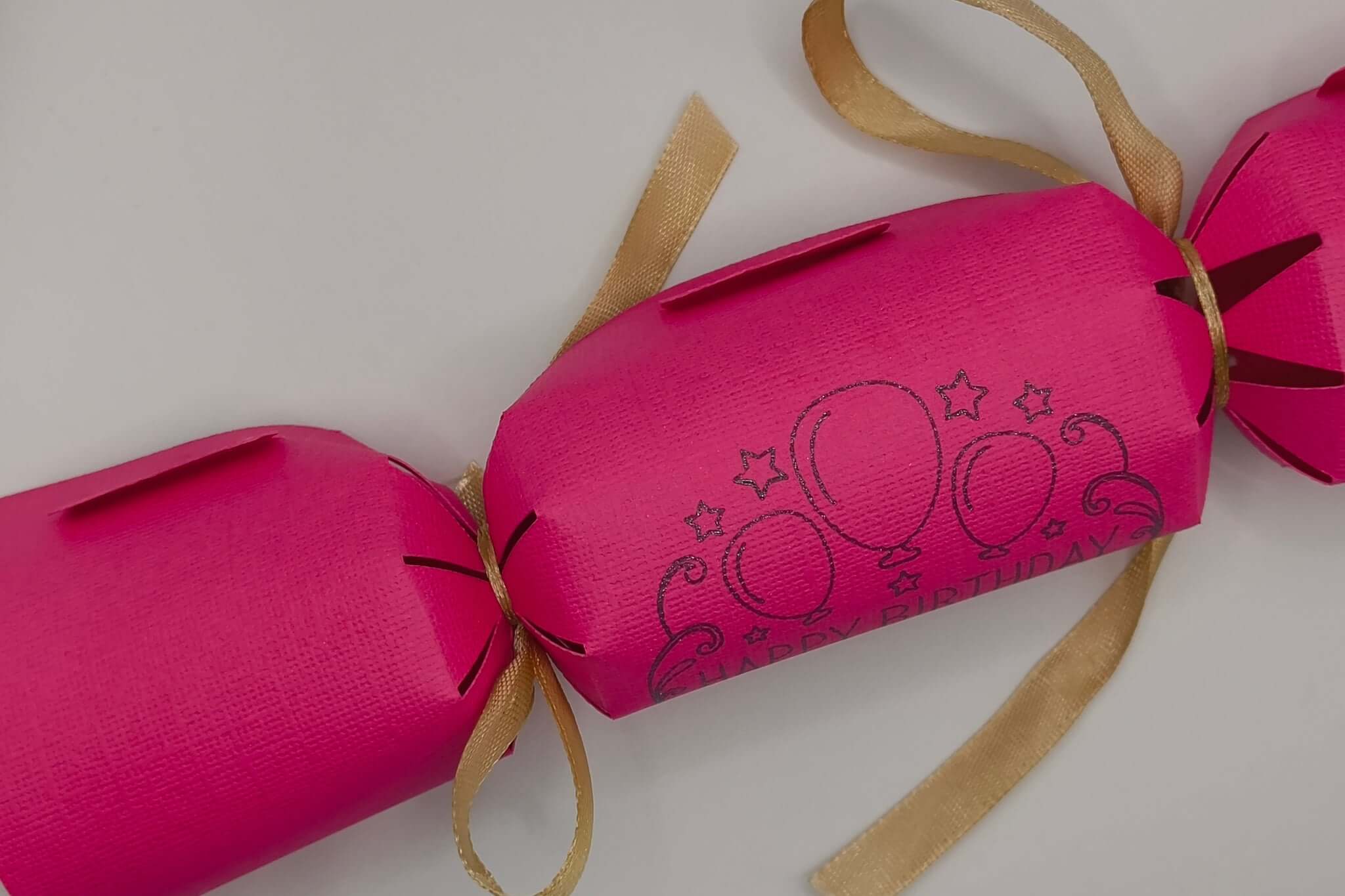 Personalised Birthday Crackers in vibrant pink with balloon designs, handmade for festive celebrations.