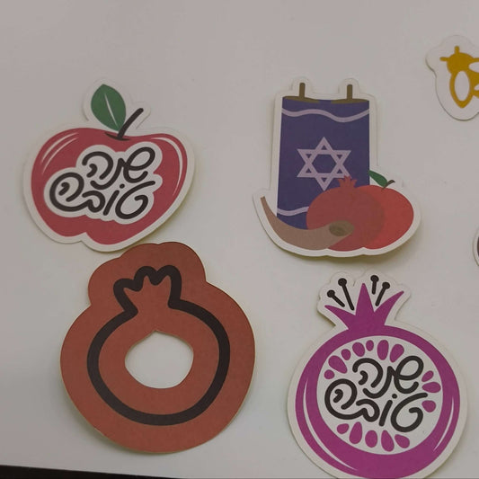 Stickers for Rosh Hashanah featuring Torah scroll, apples, pomegranates, bees, and Hebrew Shana Tova lettering.