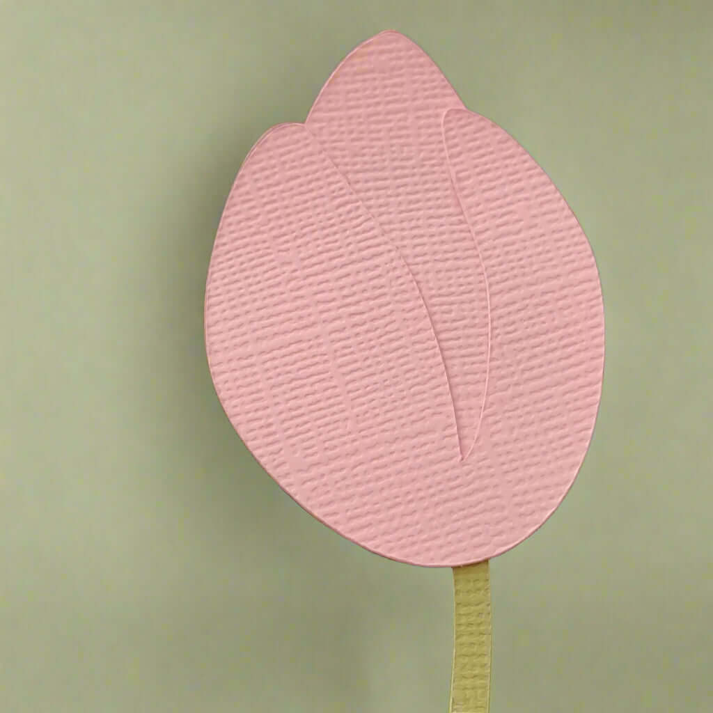 Close-up of the pink tulip flower top from the handmade cardstock place card, showing textured layered petals.