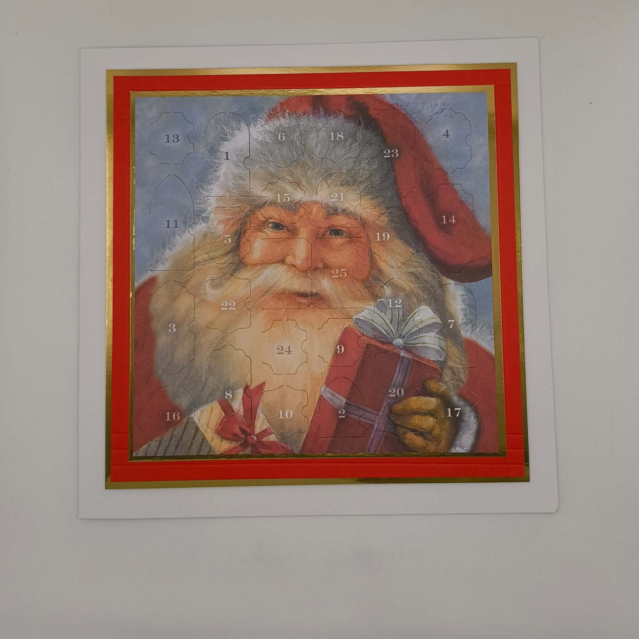 Vintage Santa Advent Calendar with numbered doors and gold border, photographed flat against a white background under bright lighting.