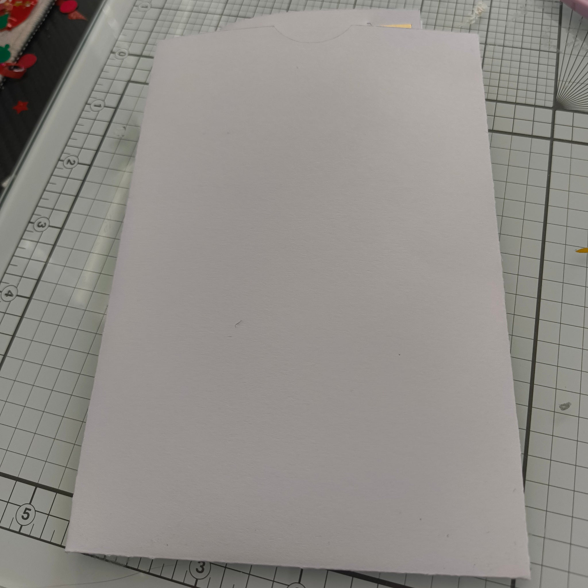 White handmade envelope for wedding money holder, plain cardstock with tab closure, shown flat on craft mat.