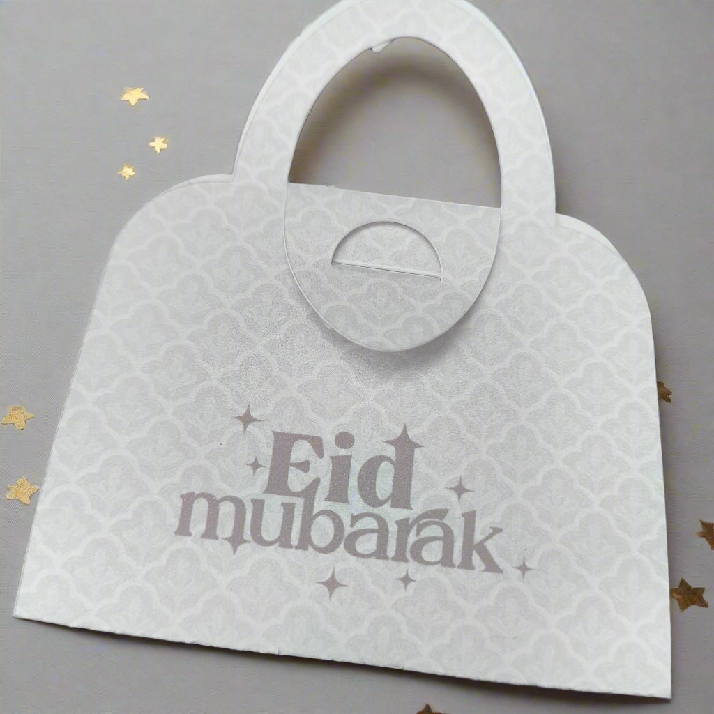 Elegant white Eid Mubarak money holder in handbag style, with delicate patterned detail and festive golden star accents.